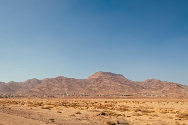 Serene desert landscape in Aqaba, Jordan with mountain views under a clear blue sky.